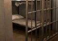 Cellule de prison avec lit superposé derrière des barreaux, illustration des détenus étrangers en Belgique