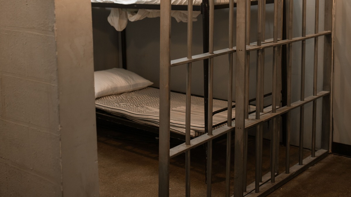 Cellule de prison avec lit superposé derrière des barreaux, illustration des détenus étrangers en Belgique